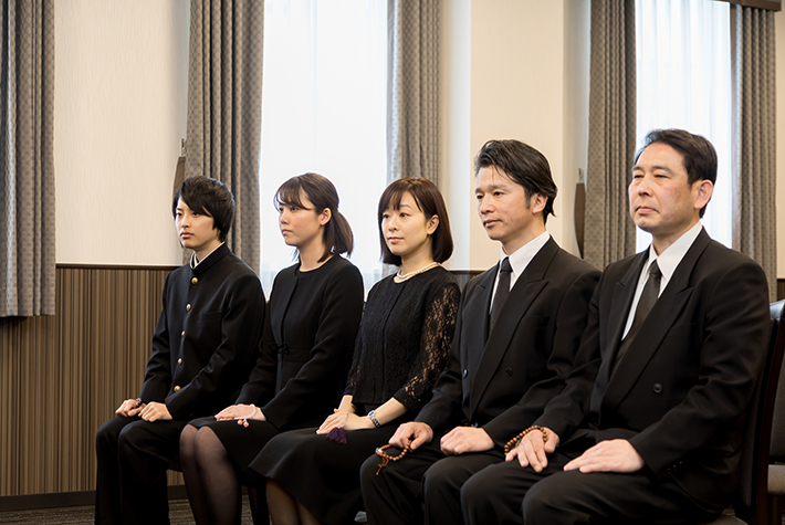 並んで座っている喪服姿の人の写真